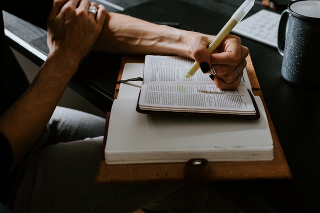 gaucher tenant un surligneur jaune au dessus d'un livre