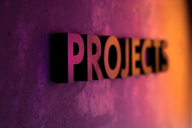 Lettering « projects » embossé et vu de profil sur fond allant du violet à l'orange avec un focus sur les premières lettres